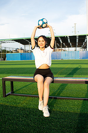 女生单人举球草地足球运动场照片