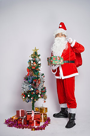 圣诞老人站着单手拿礼物摄影图