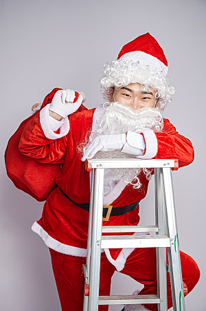 圣诞节圣诞老人爬梯子摄影图