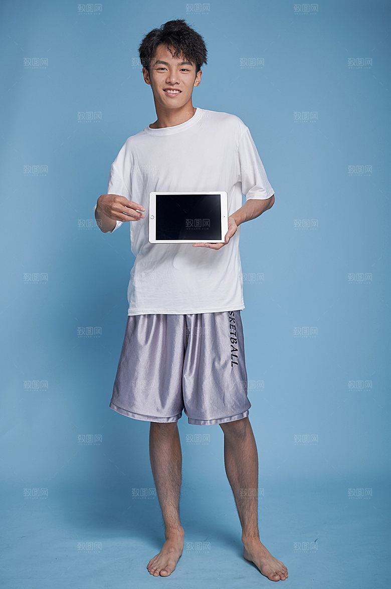 海滩男生泳装拿平板人物摄影图