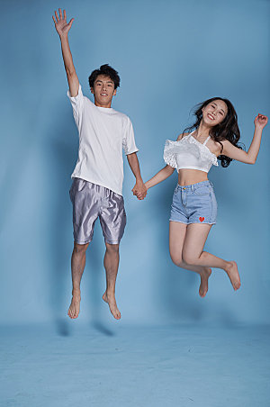 夏季情侣跳跃泳装人物摄影图