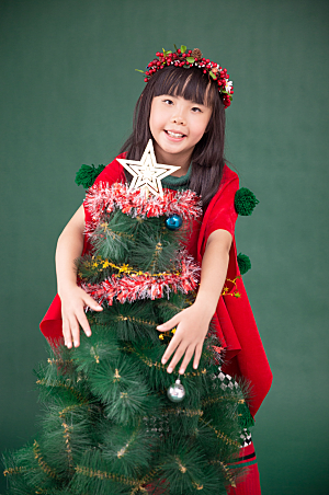 绿色圣诞树旁可爱小女孩精美摄影图